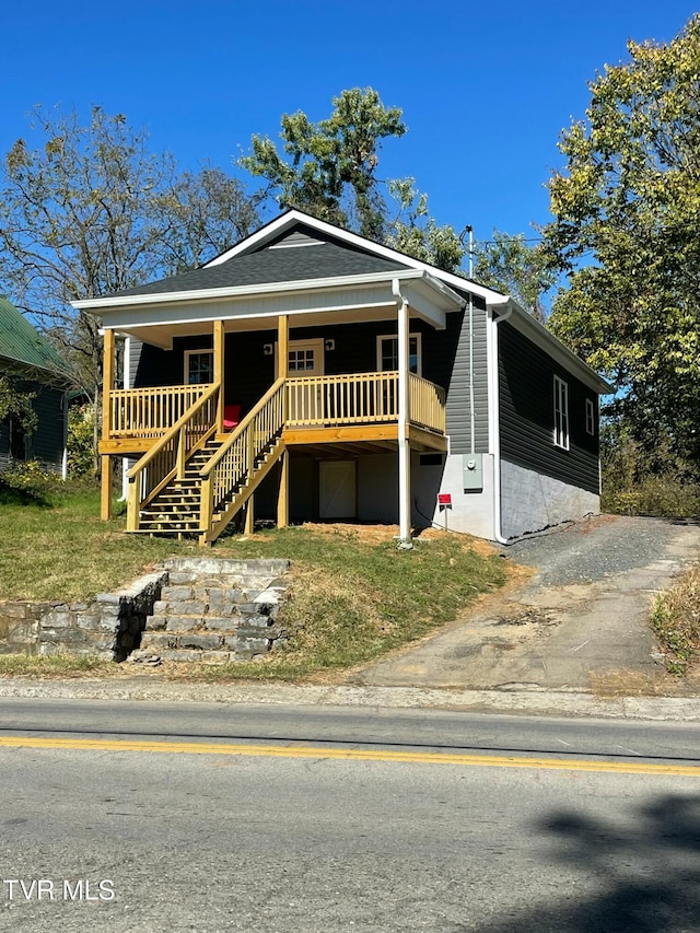 view of front of property featuring stairs, a porch, and a shingled roof