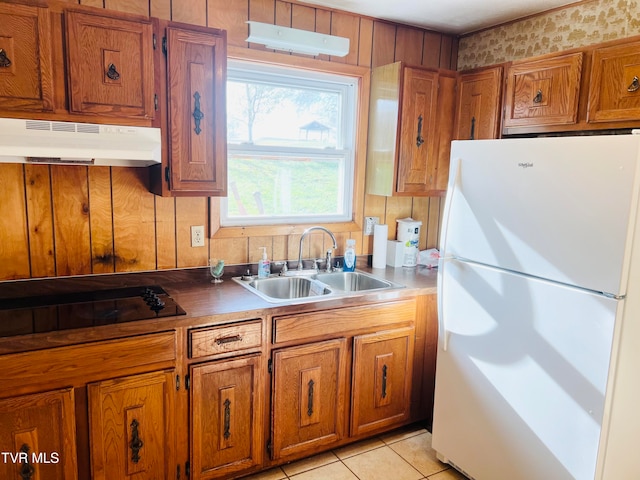 kitchen with light tile patterned floors, black stovetop, white fridge, and sink