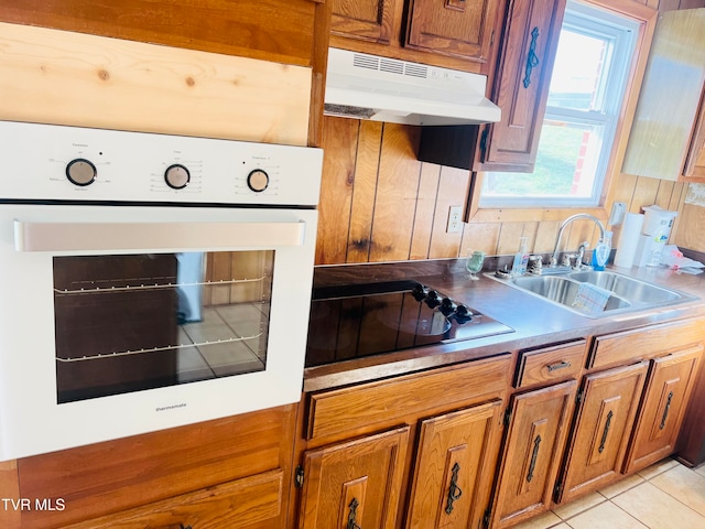 kitchen with white oven, black electric cooktop, sink, and light tile patterned flooring