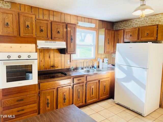 kitchen with wood walls, white appliances, sink, and light tile patterned floors