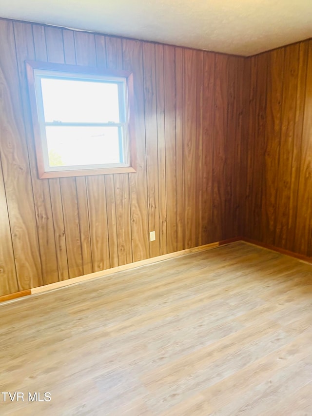 empty room with wooden walls and light hardwood / wood-style flooring