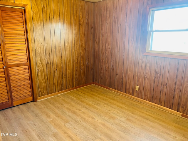 empty room featuring wood walls and light hardwood / wood-style floors