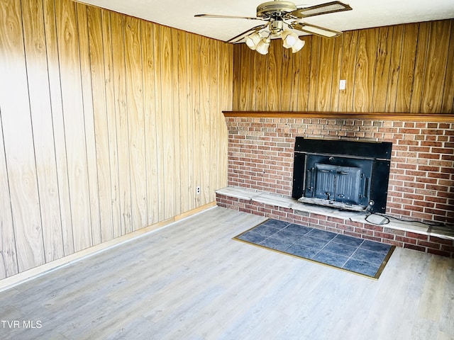 128 Graybeal Dr, Castlewood, VA 24224 - unfurnished living room featuring wood finished floors, a ceiling fan, wooden walls, baseboards, and a brick fireplace