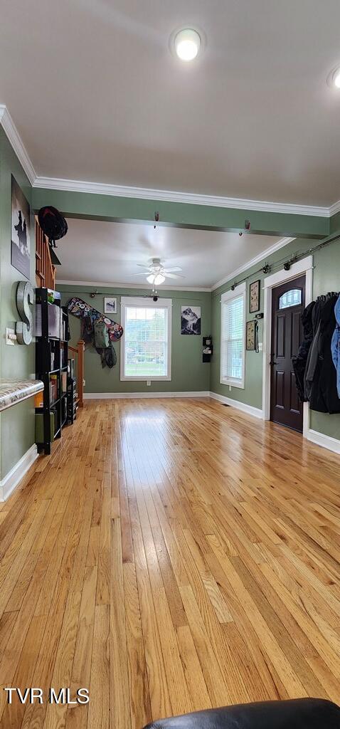 unfurnished living room with crown molding, ceiling fan, and light wood-type flooring