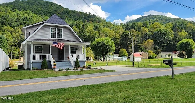 view of front facade featuring a mountain view, a porch, and a front lawn