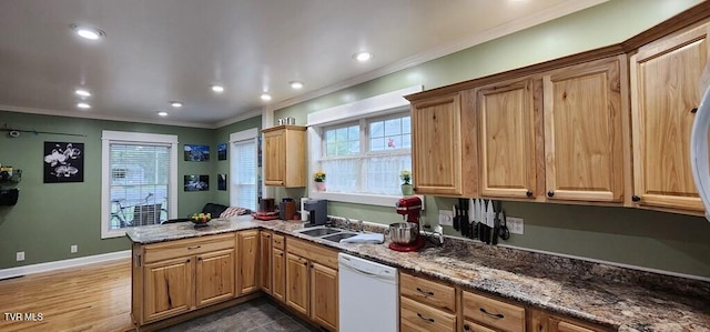 kitchen with kitchen peninsula, white dishwasher, crown molding, and dark stone countertops