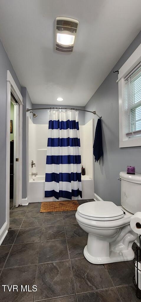 bathroom featuring toilet and shower / tub combo with curtain