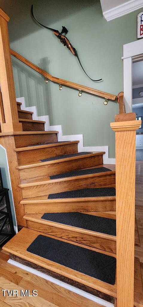 stairs featuring wood-type flooring and ornamental molding