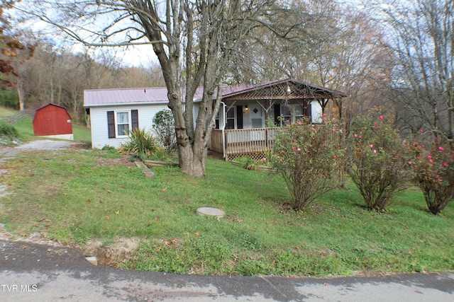 view of front of property featuring a porch, a shed, and a front lawn