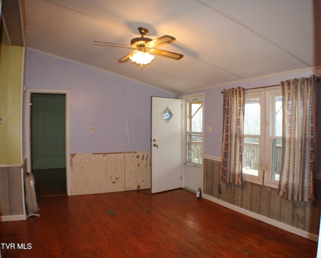 entryway featuring wood walls, dark wood-type flooring, vaulted ceiling, ceiling fan, and ornamental molding