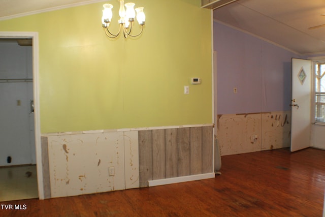 interior space with ceiling fan with notable chandelier, vaulted ceiling, wooden walls, crown molding, and hardwood / wood-style floors