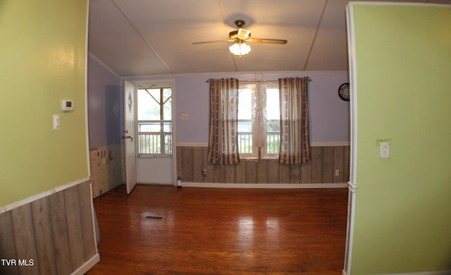 spare room with ceiling fan, wood walls, dark hardwood / wood-style flooring, and lofted ceiling