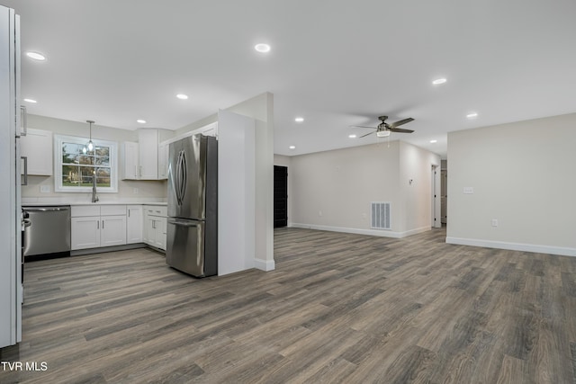 kitchen with dark wood-type flooring, white cabinets, ceiling fan, decorative light fixtures, and stainless steel appliances