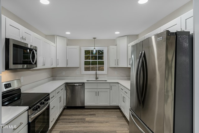 kitchen with pendant lighting, white cabinets, sink, and appliances with stainless steel finishes