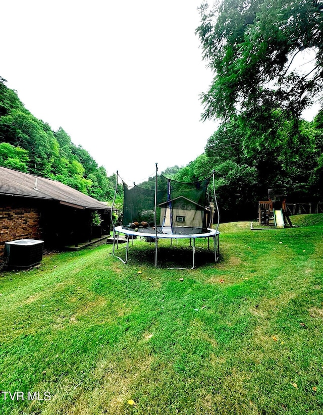 view of yard featuring a playground, cooling unit, and a trampoline