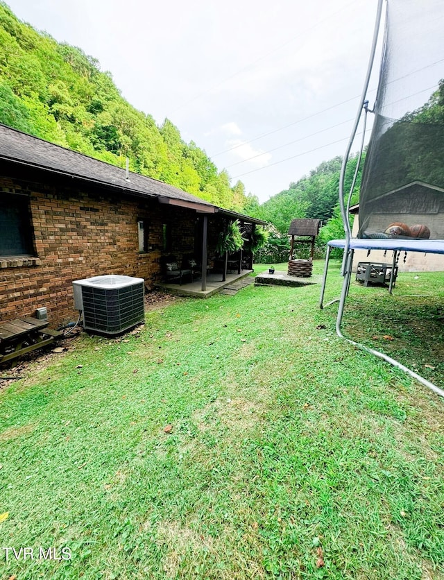 view of yard featuring a trampoline, a patio, and central AC