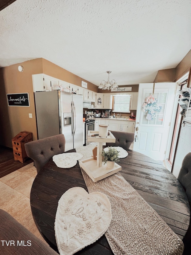 dining room featuring an inviting chandelier, lofted ceiling, a textured ceiling, and light hardwood / wood-style flooring