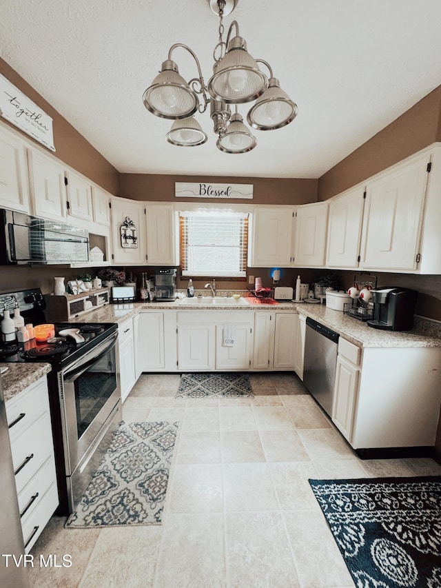 kitchen with pendant lighting, white cabinets, sink, a textured ceiling, and appliances with stainless steel finishes