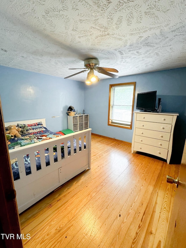 bedroom featuring ceiling fan, a textured ceiling, and light hardwood / wood-style flooring