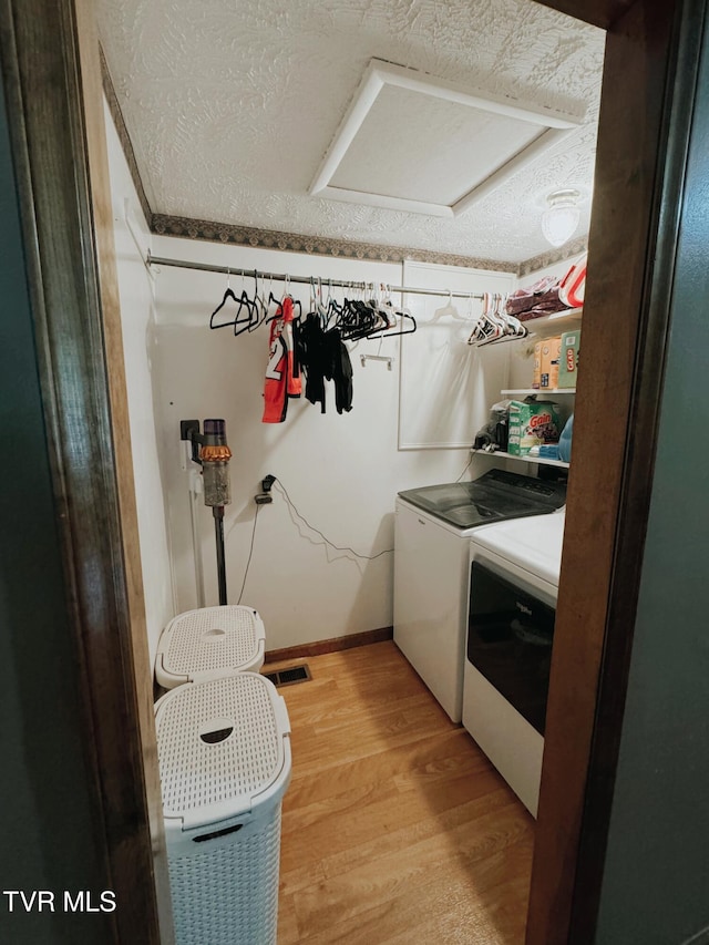 washroom featuring washer and clothes dryer, wood-type flooring, and a textured ceiling