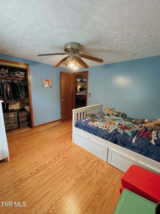 bedroom with hardwood / wood-style floors, a textured ceiling, a closet, and ceiling fan