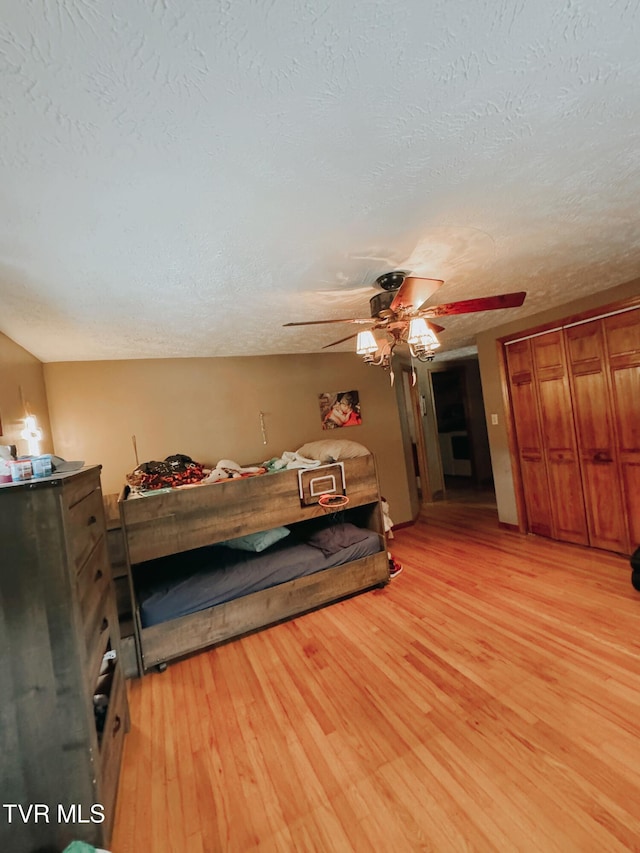 bedroom with a closet, ceiling fan, light hardwood / wood-style flooring, and a textured ceiling