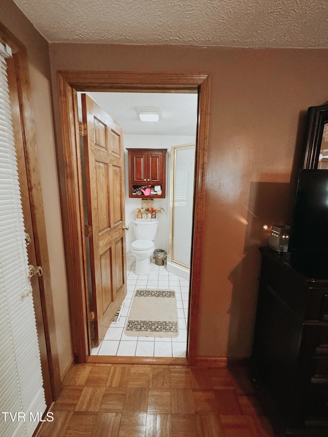 hallway featuring light tile patterned flooring and a textured ceiling