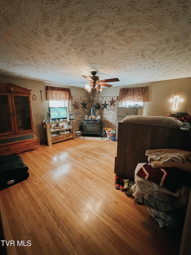 unfurnished living room featuring wood-type flooring, a wood stove, and a wealth of natural light