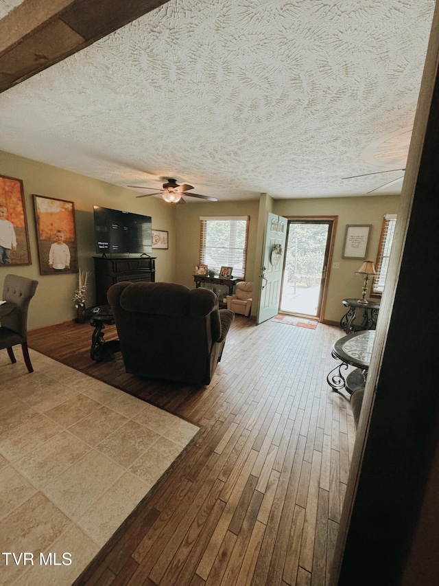 living room with ceiling fan, wood-type flooring, and a textured ceiling