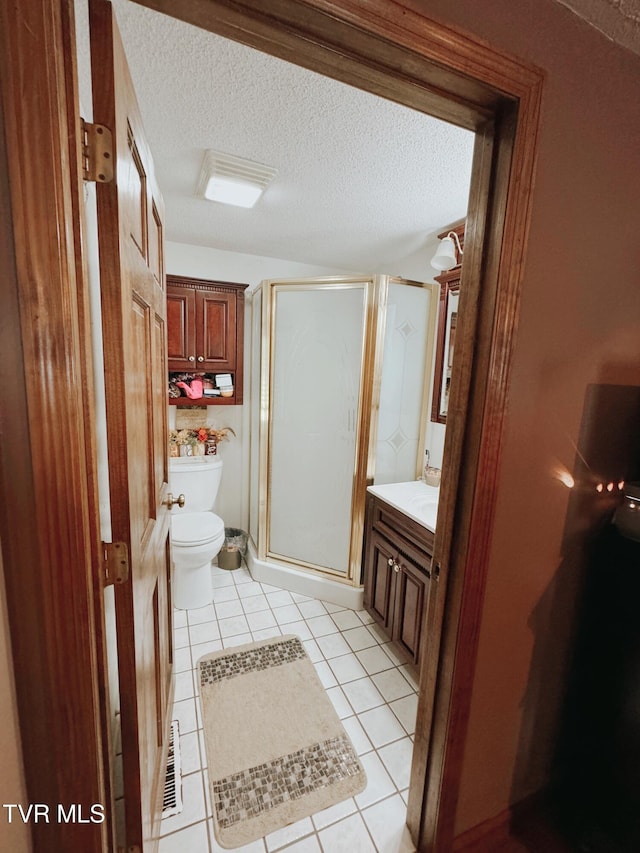 bathroom with vanity, tile patterned flooring, toilet, a textured ceiling, and an enclosed shower