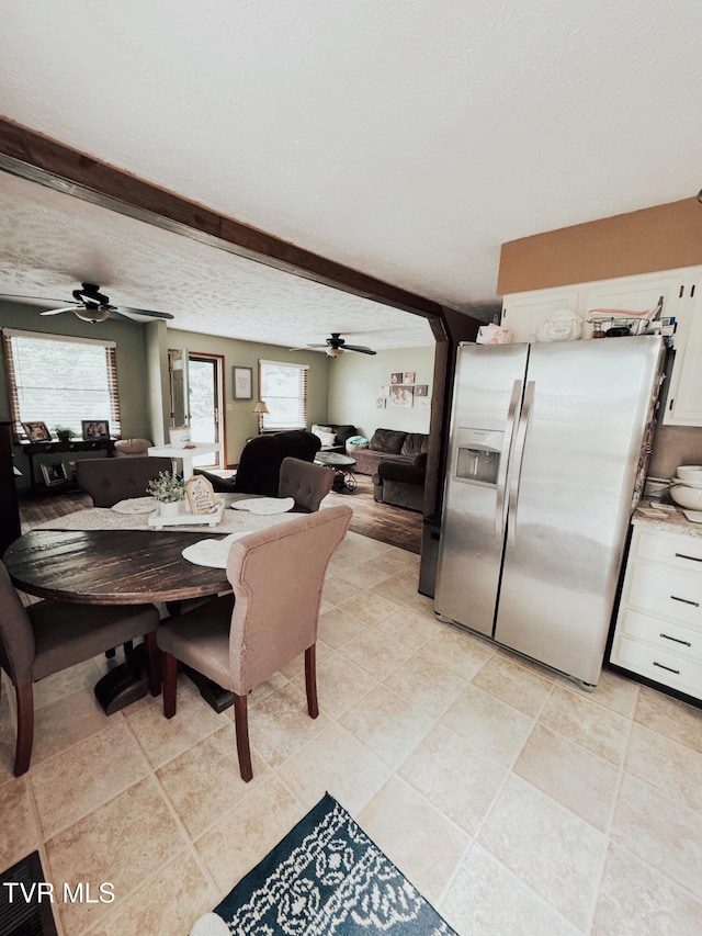 dining area with beamed ceiling, ceiling fan, light tile patterned floors, and a textured ceiling