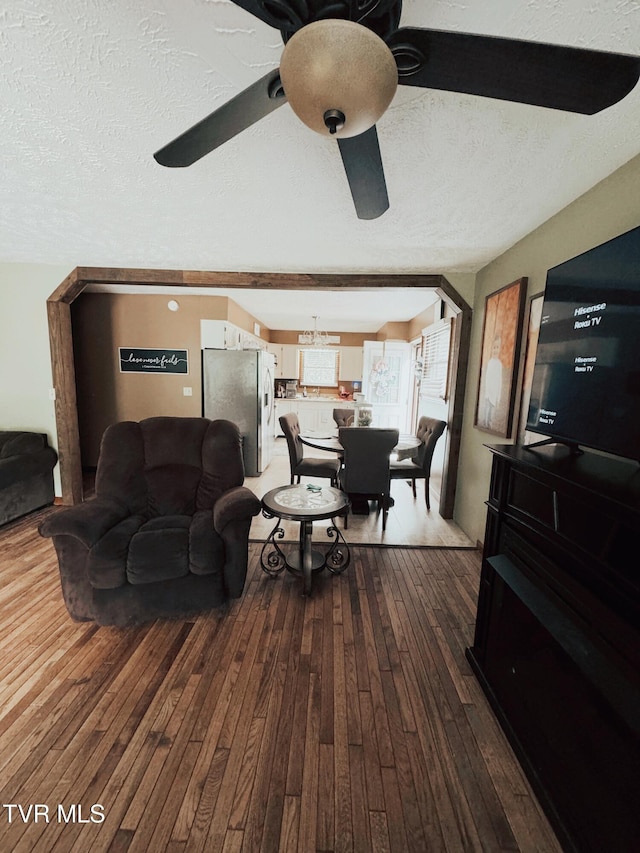 living room with ceiling fan, a textured ceiling, and hardwood / wood-style flooring