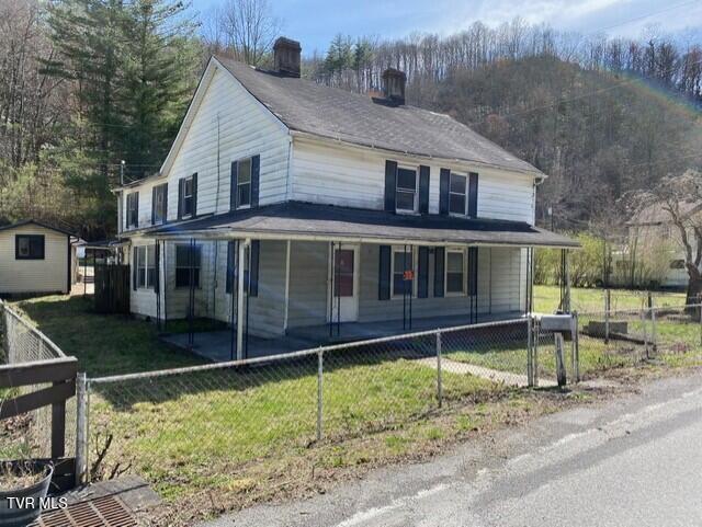 view of front facade featuring a porch, a storage shed, and a front yard