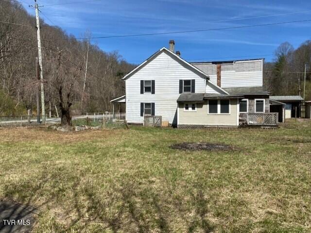 rear view of property featuring a lawn and a carport