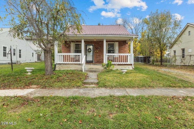 bungalow featuring covered porch and a front yard