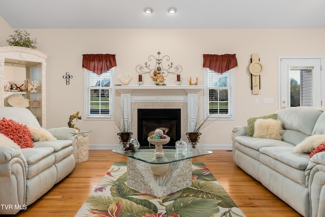 living room featuring a tile fireplace, light wood-type flooring, and a wealth of natural light