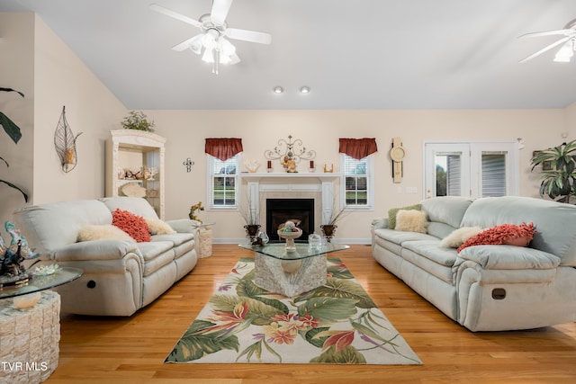 living room with ceiling fan, light hardwood / wood-style floors, and a tile fireplace