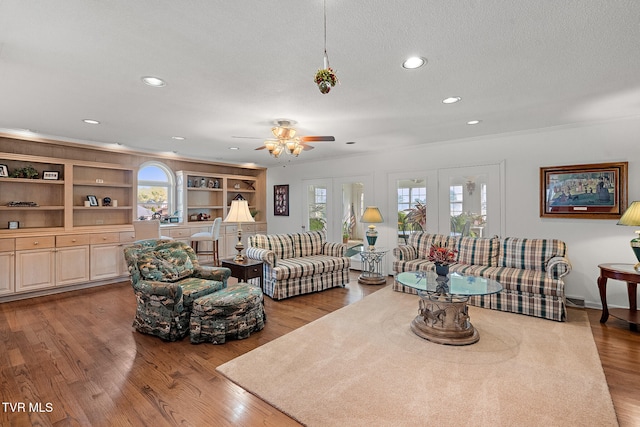 living room featuring ceiling fan, light hardwood / wood-style floors, and a textured ceiling