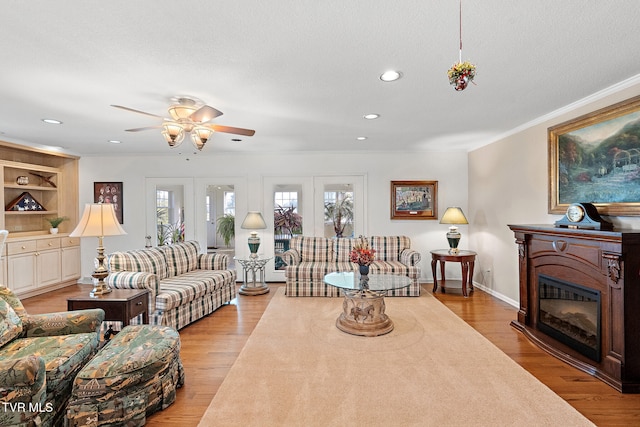 living room with french doors, light wood-type flooring, a textured ceiling, and ornamental molding