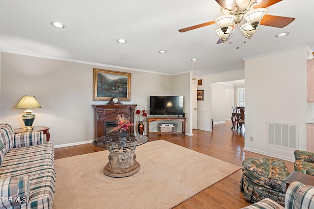 living room with hardwood / wood-style floors, ceiling fan, and ornamental molding