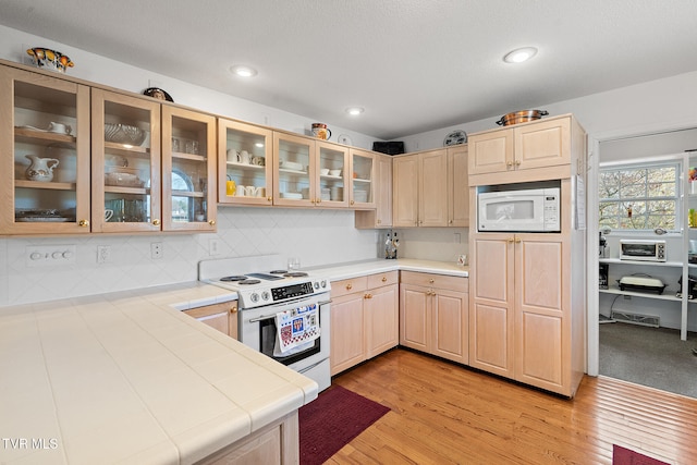 kitchen featuring tile countertops, light hardwood / wood-style floors, white appliances, and light brown cabinetry