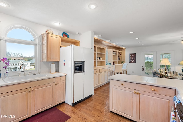 kitchen featuring light brown cabinets, white fridge with ice dispenser, a healthy amount of sunlight, and sink