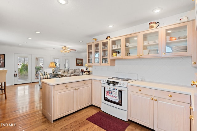 kitchen with kitchen peninsula, tasteful backsplash, white electric range oven, ceiling fan, and light hardwood / wood-style floors