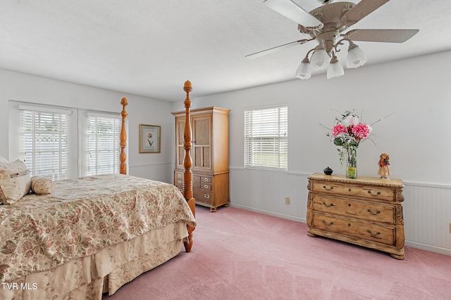 bedroom with a textured ceiling, ceiling fan, light carpet, and wood walls