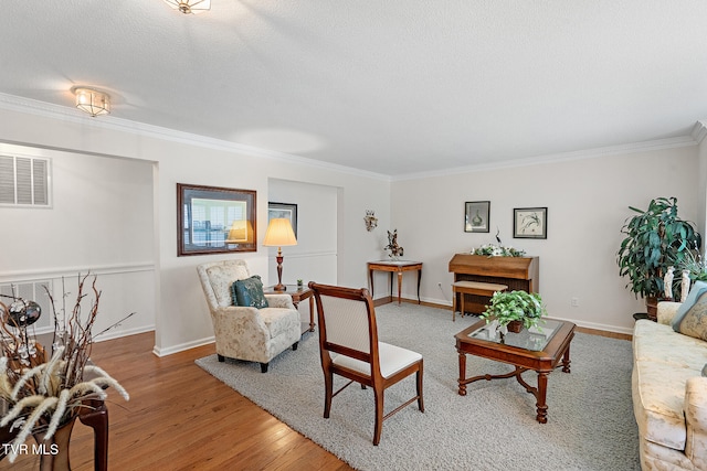 living room featuring a textured ceiling, wood-type flooring, and ornamental molding