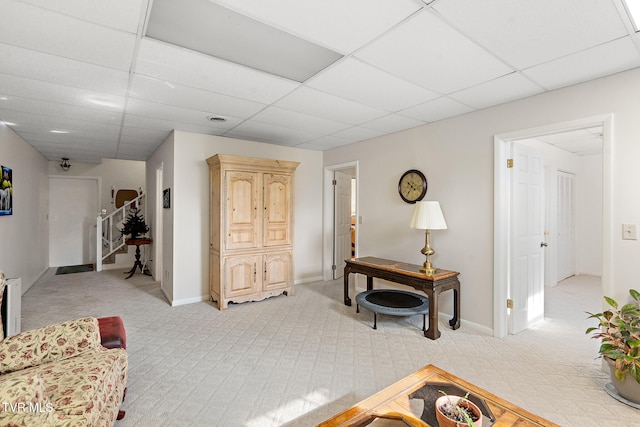 corridor featuring light carpet and a paneled ceiling