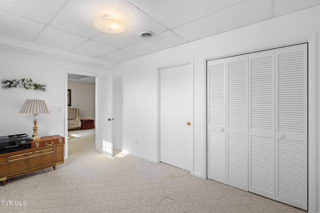 carpeted bedroom featuring a paneled ceiling and a closet