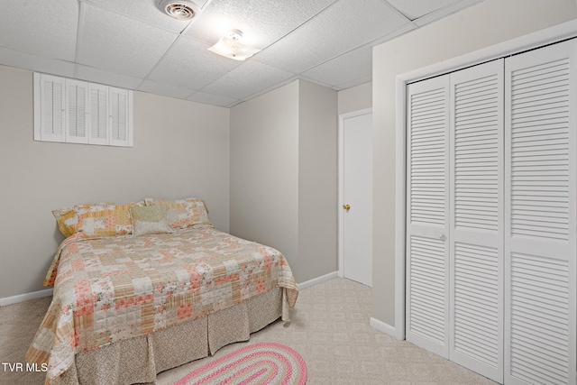 carpeted bedroom with a closet and a drop ceiling