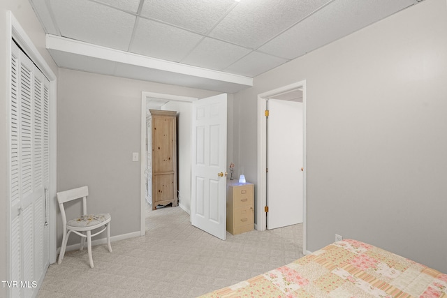 carpeted bedroom featuring a paneled ceiling and a closet