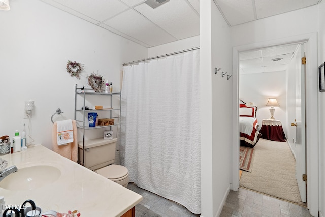 bathroom with vanity, toilet, and a drop ceiling